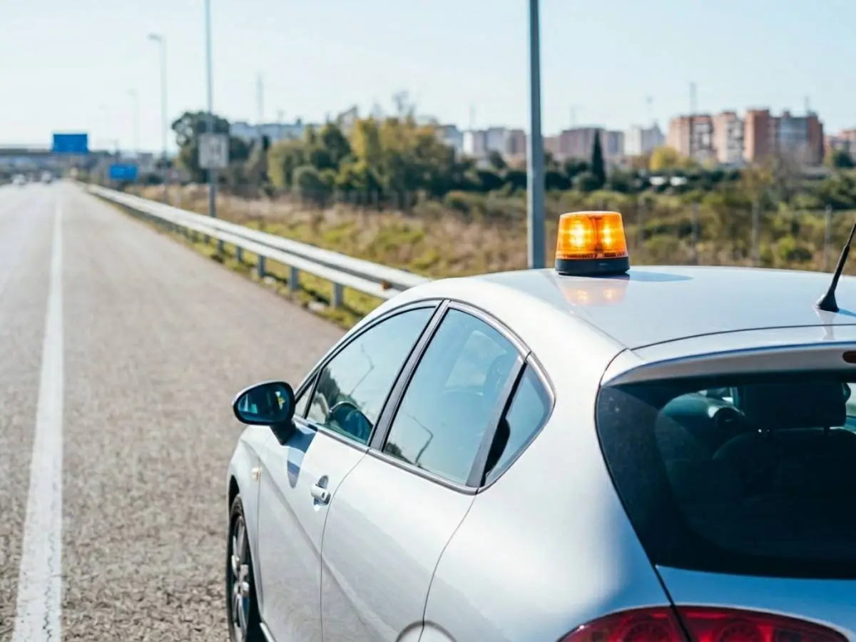 Coche con baliza V-16 en carretera al mediodía