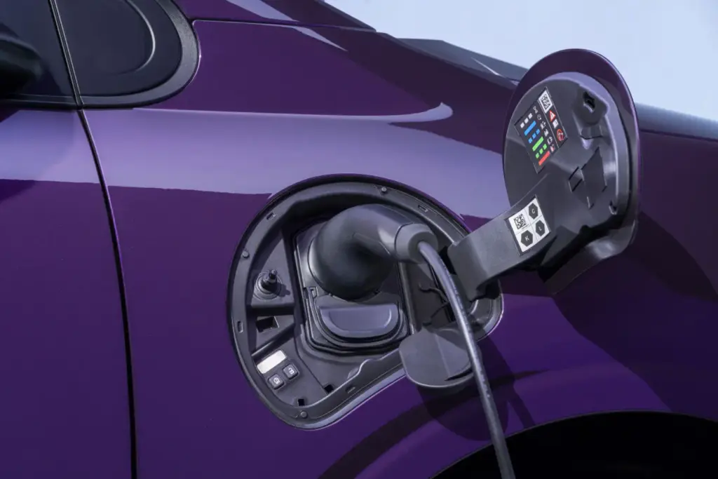 Nissan presenta el nuevo PIXO, su eléctrico urbano de acceso 32 Motor16 Photograph shows open Nissan PIXO fuel-filler compartment on a glossy purple car, highlighting vehicle refueling components.