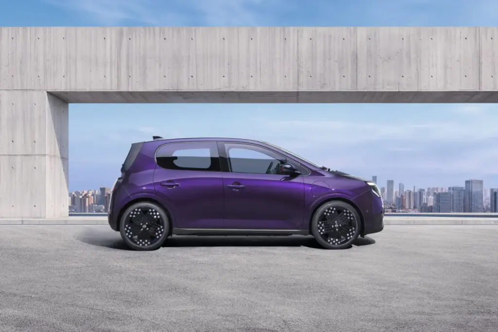 Nissan presenta el nuevo PIXO, su eléctrico urbano de acceso 1 Motor16 Photograph showcasing a purple Nissan PIXO parked on a rooftop terrace. Side profile highlights aerodynamic shape, black alloy wheels concrete architectural frame, and city skyline backdrop.